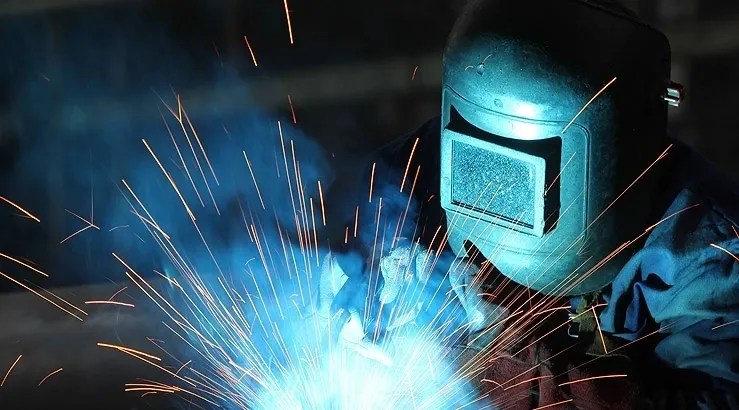 A person welding with blue and orange sparks