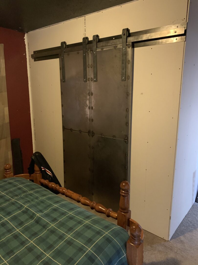 A bedroom with a bed and a large metal door.